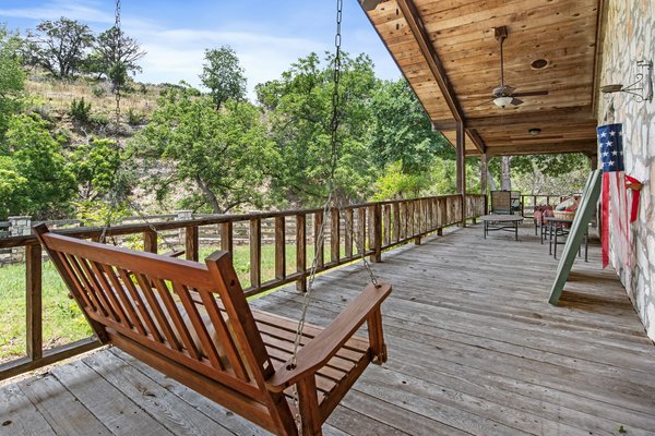 Covered porch with wooden swing and Hill Country view